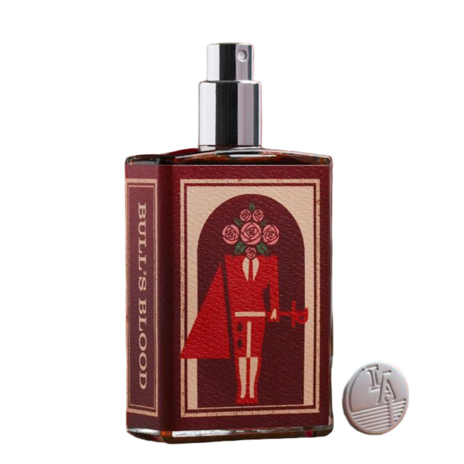 Perfume bottle with decorative label on a wooden surface with books in the background