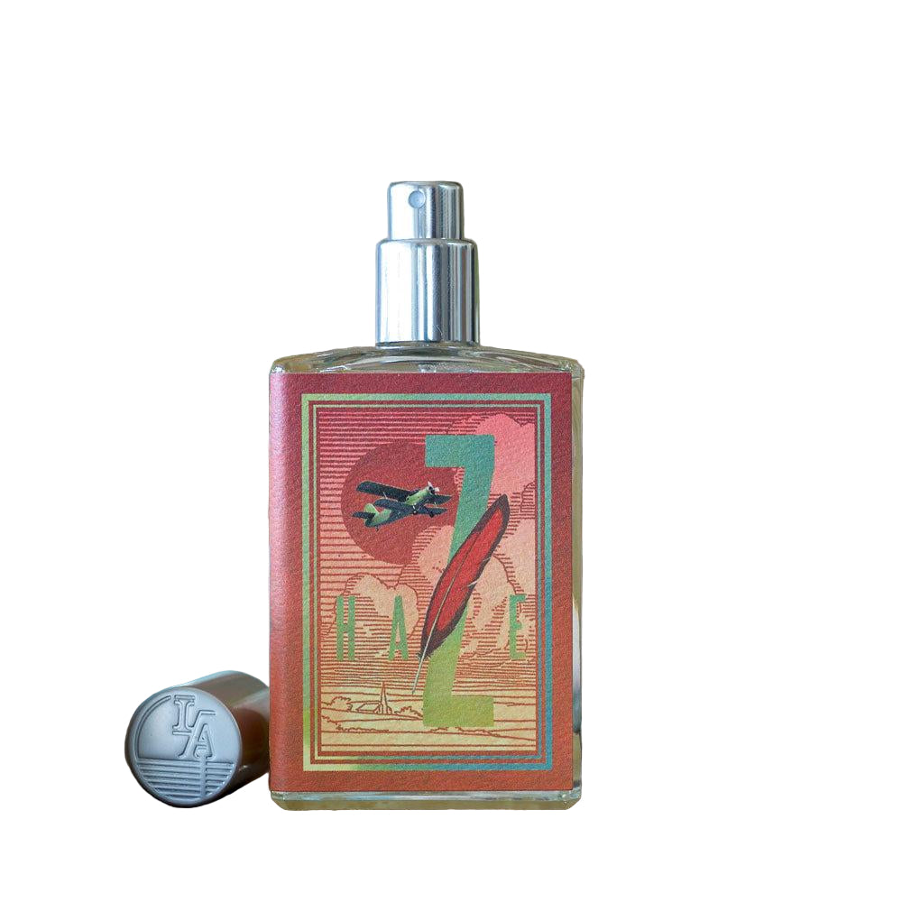 Perfume bottle with decorative label on a wooden surface with plants in the background
