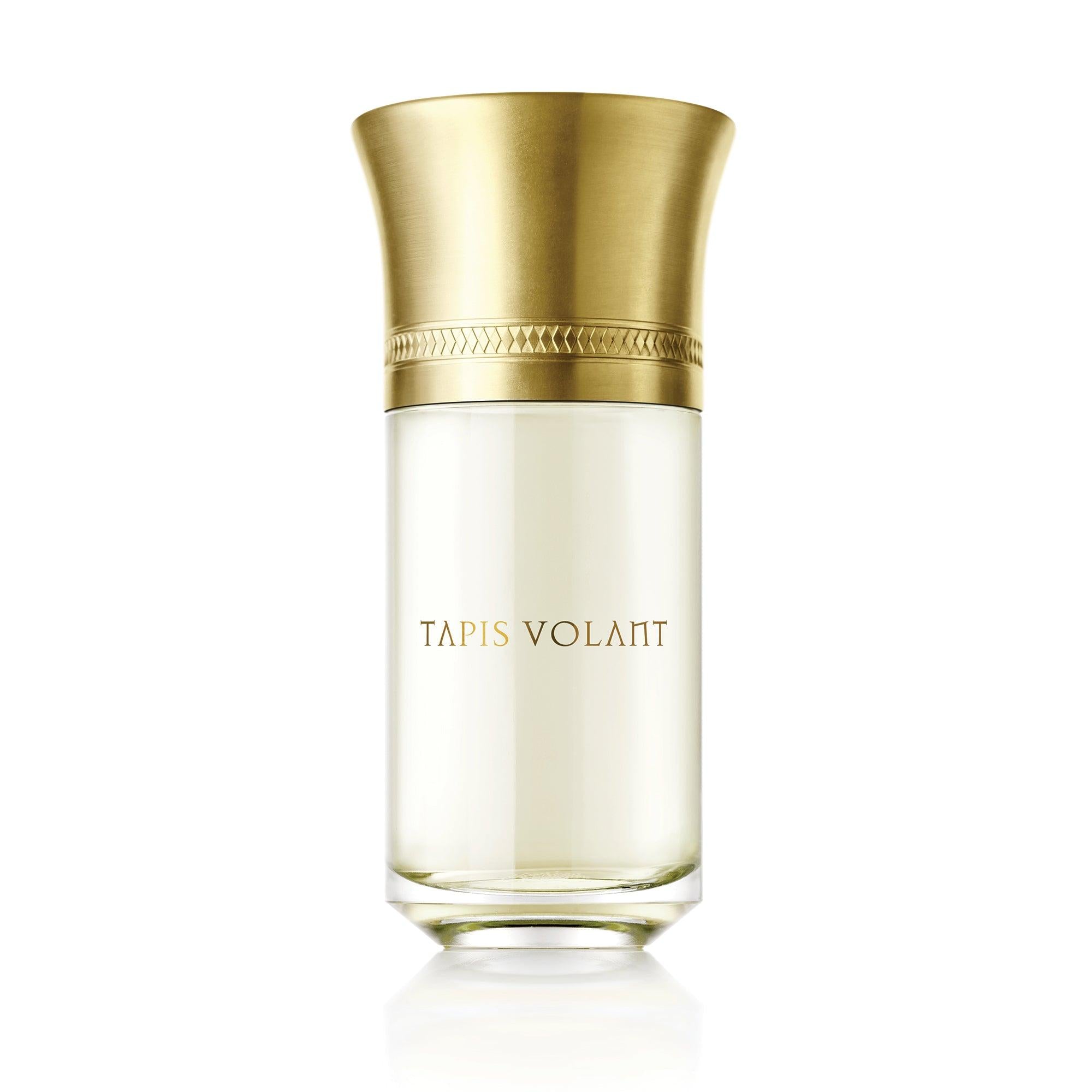 Perfume bottle with gold cap and 'Tapis Volant' branding on a white background