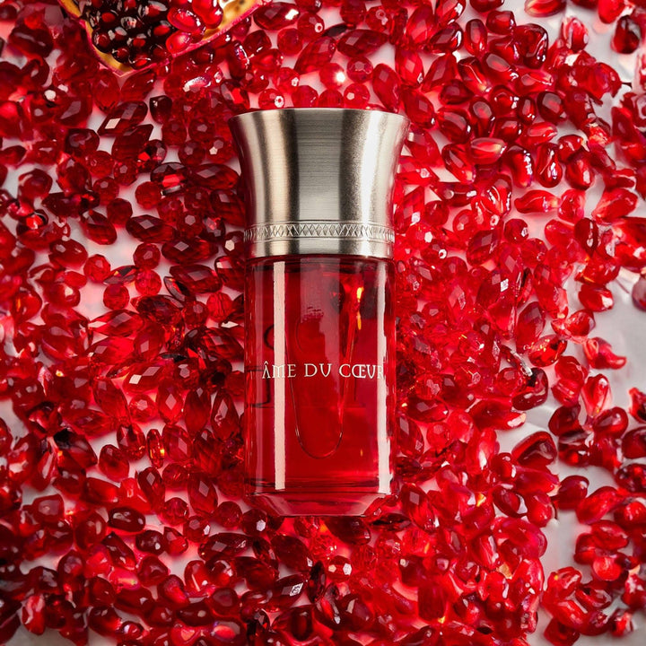 Red serum bottle with silver cap on a bed of red pomegranate seeds