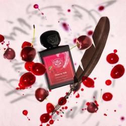 Perfume bottle with cherry design surrounded by cherries and a feather on a white background